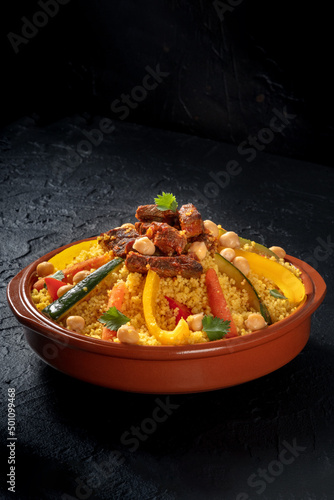 Couscous with meat and vegetables, traditional Arabic food, on a black slate background