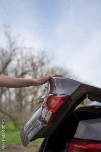 Person closes the trunk of the car. Side view of the vehicle. The concept of logistics, delivery and transportation