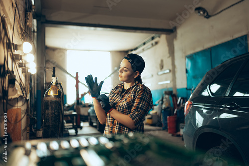 Destroying gender stereotypes. Young woman auto mechanic working at auto service station using different work tools. Gender equality. Work, occupation, car