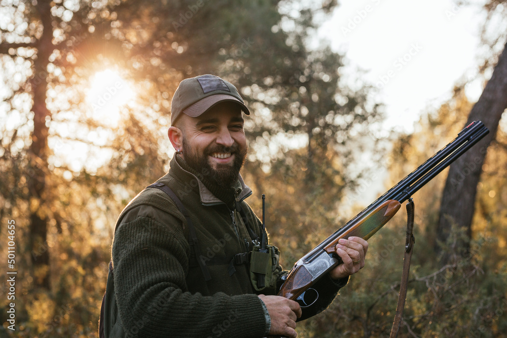 Fototapeta premium Hunter holding his shotgun while smiling looking at camera