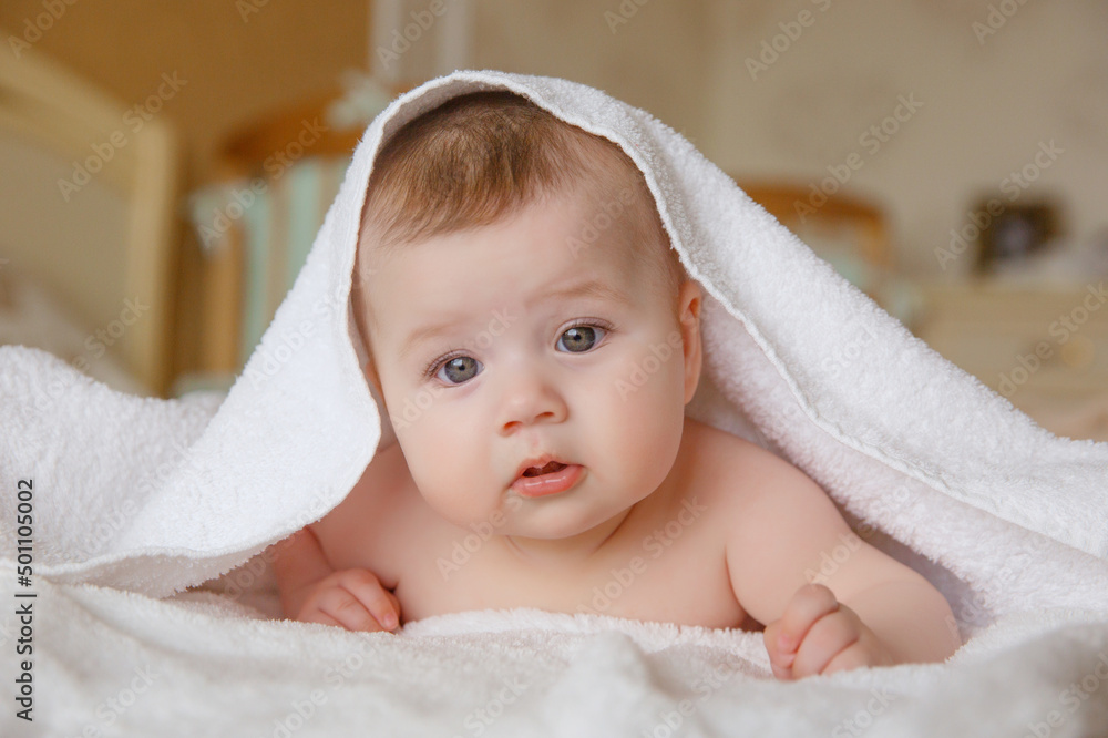 baby girl in a white towel or blanket in a white bedroom. A newborn baby is resting in bed. Portrait of a Caucasian child. The concept of kindergarten and infancy.children's goods baby girl in a white towel or blanket in a white bedroom. A newborn baby is resting in bed. Portrait of a Caucasian child. The concept of kindergarten and infancy.children's goods