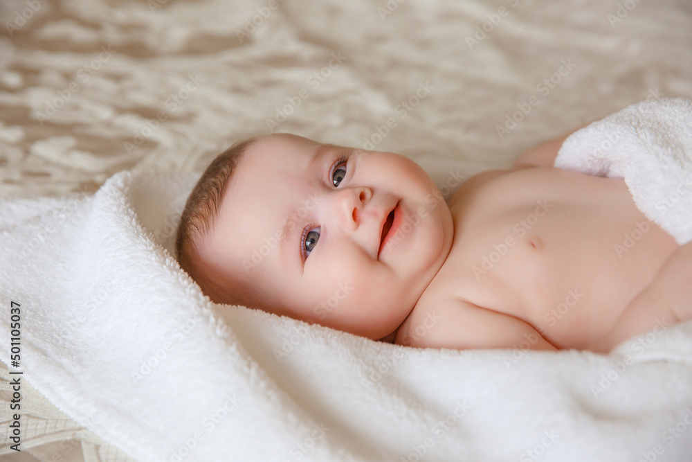 baby girl in a white towel or blanket in a white bedroom. A newborn baby is resting in bed. Portrait of a Caucasian child. The concept of children's goods baby girl in a white towel or blanket in a white bedroom. A newborn baby is resting in bed. Portrait of a Caucasian child. The concept of children's goods