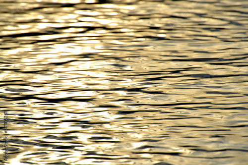 Golden ocean water, photo background. Beautiful summer sea, sunset time. Ocean surface natural background. Backdrop for lettering, cards, banner, design and decor elements. 