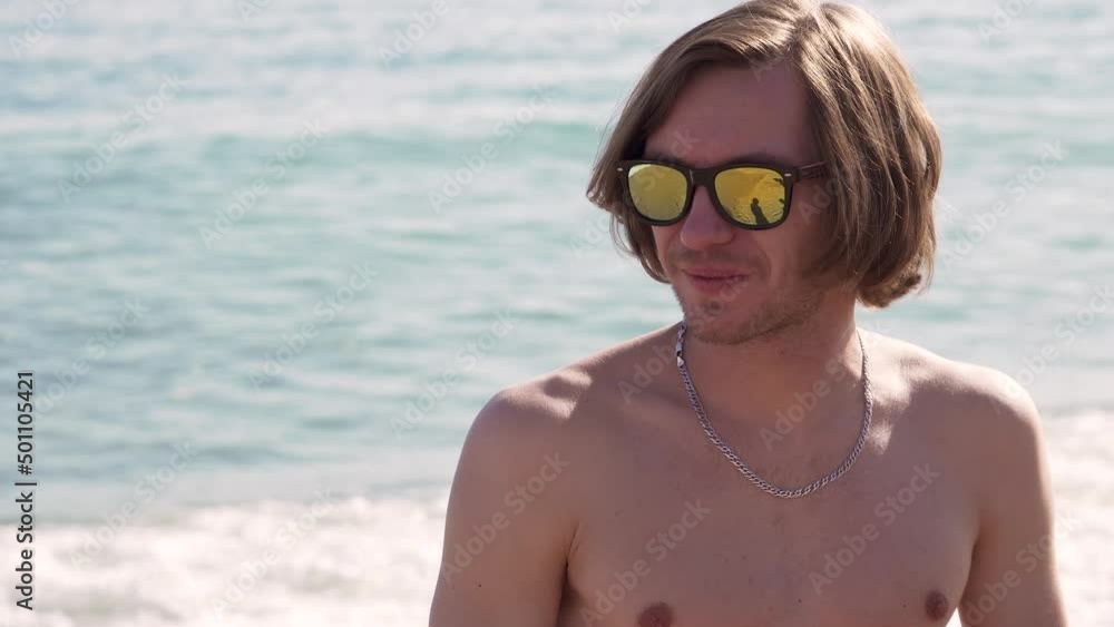 Hippie shirtless man smiling as the waves hit the beach Hippie shirtless man smiling as the waves hit the beach