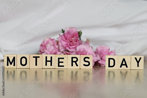Różowe goździki z napisem Dzień Matki po angielsku na jasnym tle