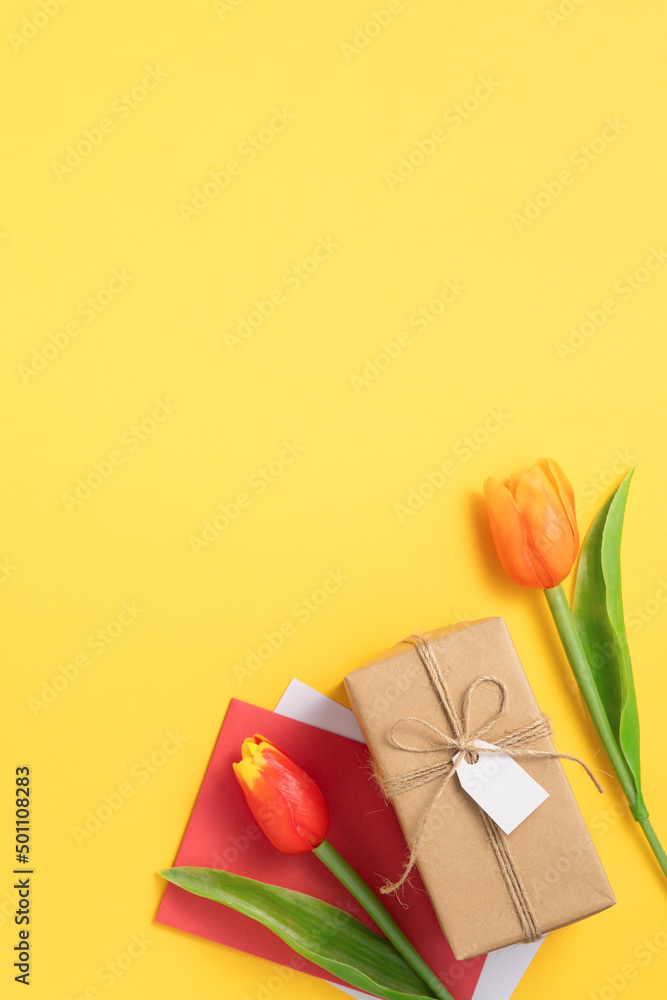 Mother's day background. Top view of gift with tulip bouquet on yellow table background Mother's day background. Top view of gift with tulip bouquet on yellow table background