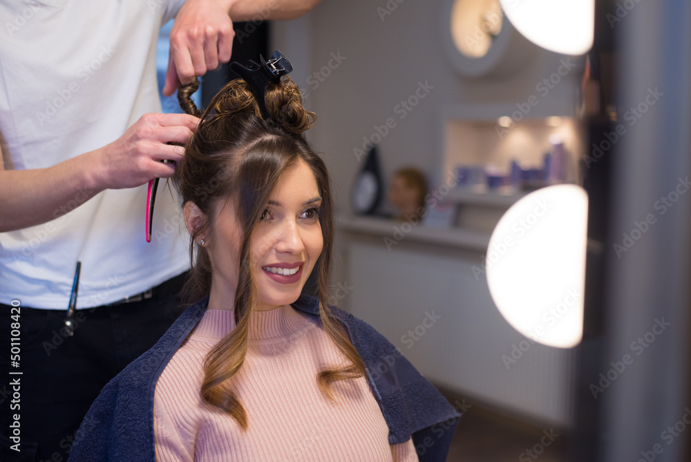 Fototapeta premium Young woman getting new hairstyle from hairdresser in the modern hair salon