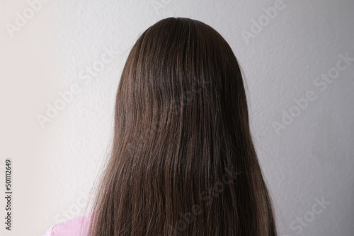 european young girl with natural long brown thick hair, stands with her back, rear view, haircut care concept, hair care cosmetics, trichologists research
