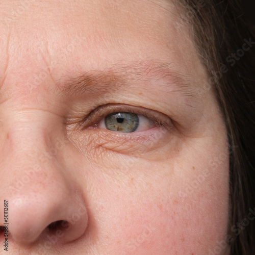 close up part of mature woman 50 years face, human eye, small wrinkles around eyes, overhang, concept of surveillance, vision examination, cosmetic anti-aging procedures