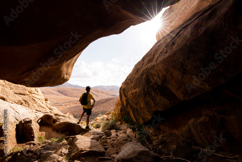 Man enjoying the view standing inside the sandstone canyons, Barranco de las Penitas, Fuerteventura, Canary Islands photo