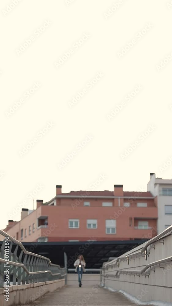 Vertical view of young woman riding an electric scooter going down the ramp Vertical view of young woman riding an electric scooter going down the ramp