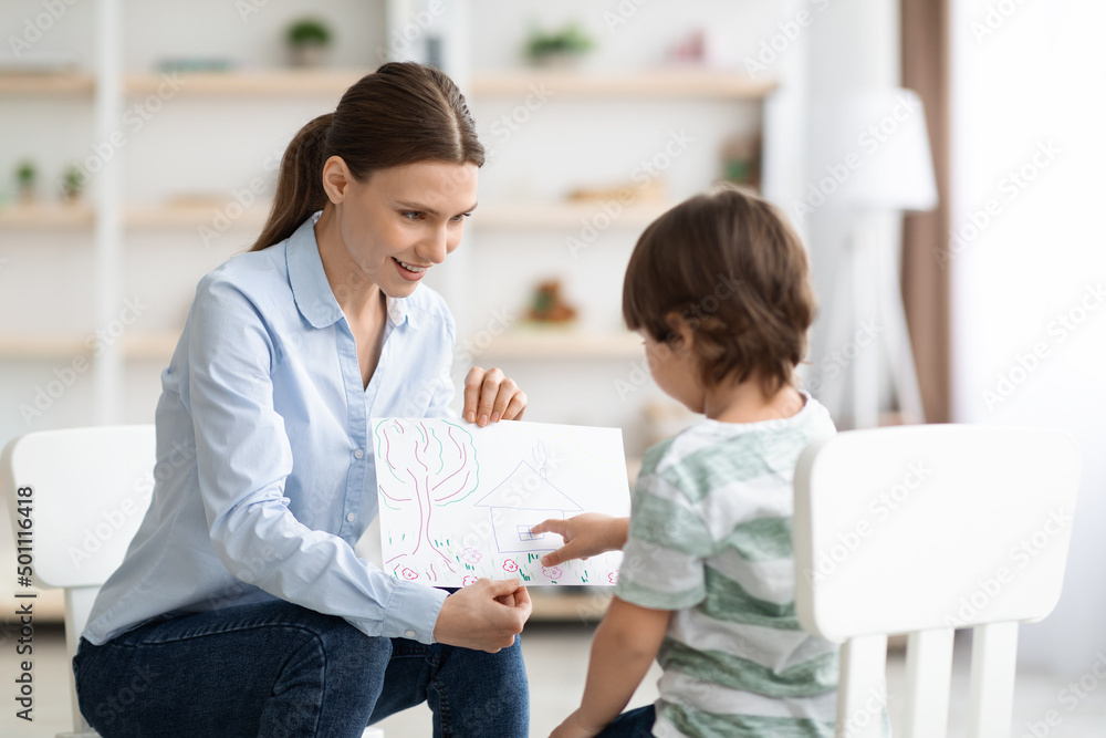 Little boy describing picture to professional woman psychologist, doctor evaluating mental health of patient Little boy describing picture to professional woman psychologist, doctor evaluating mental health of patient
