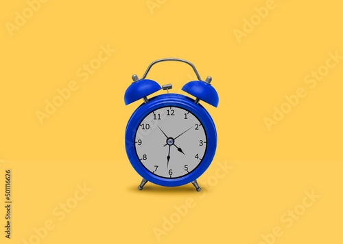 Alarm clock. Template with copy space. Blue classic metal clock on bright yellow background