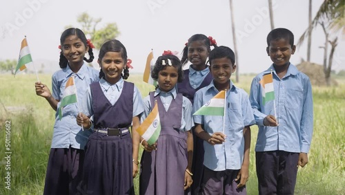 group of happy smiling viallge school kids in unifrom holding Infian flag by looking at camera during independence day celebrations - conept of patriotismsm, diversity and real people. photo