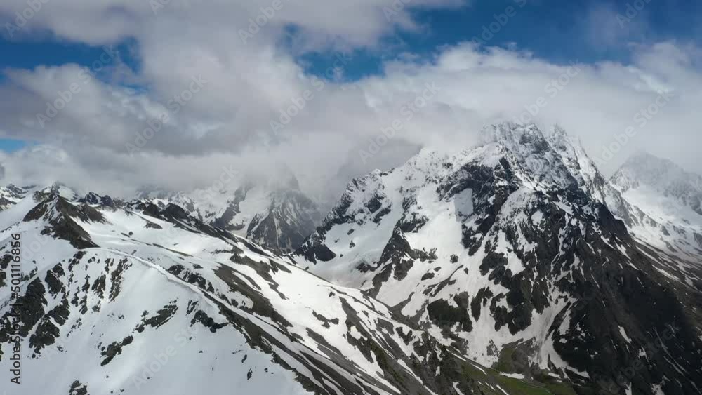 Air flight through mountain clouds over beautiful snow-capped peaks of mountains and glaciers. Air flight through mountain clouds over beautiful snow-capped peaks of mountains and glaciers.