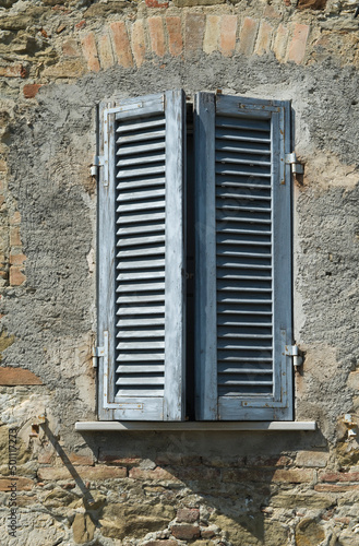 Fenster mit geschlossenen Fensterläden in einer verwitterten Wand