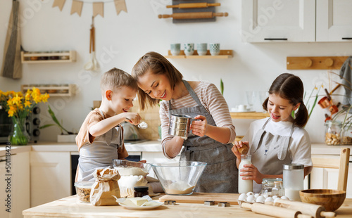 Tela Happy woman and cute children cooking together in kitchen
