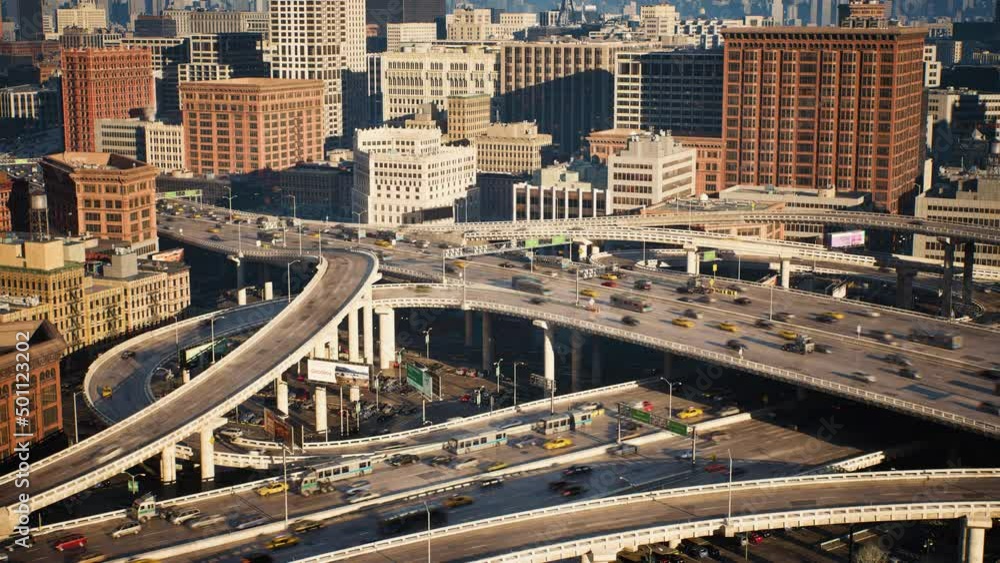 View to the motorway intersection in New York. A lot of road crossings in the megapolis. Active urban traffic. Expressway, high skyscrapers downtown on horizon. Drone top shots. View to the motorway intersection in New York. A lot of road crossings in the megapolis. Active urban traffic. Expressway, high skyscrapers downtown on horizon. Drone top shots.