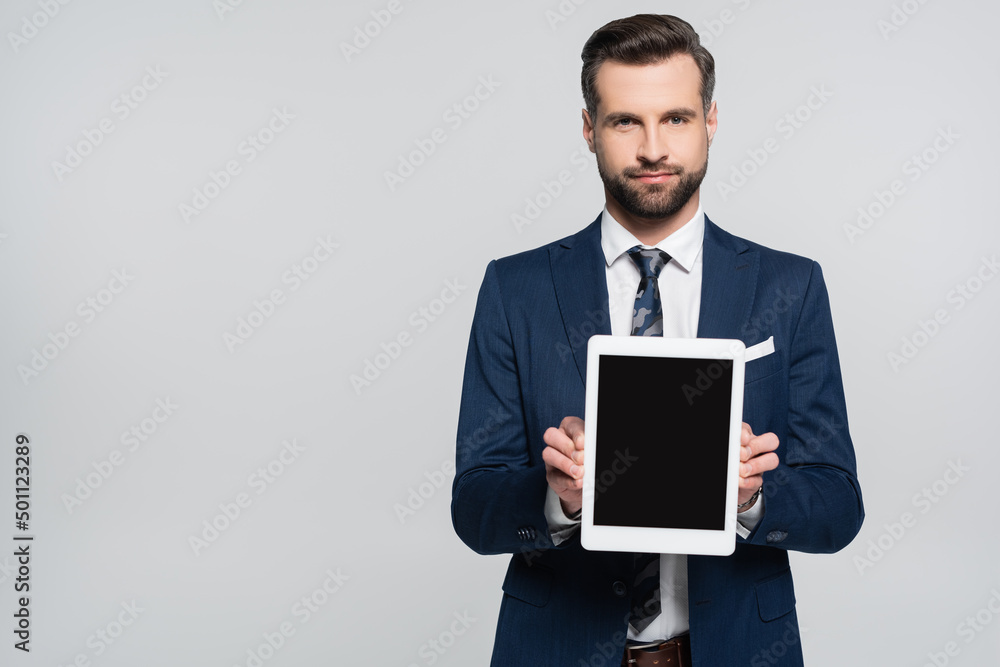 businessman in blue blazer showing digital tablet with blank screen isolated on grey.