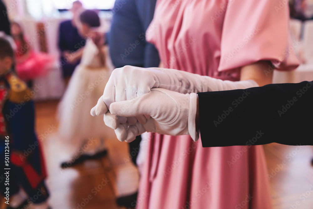 Couples dance on the historical costumed ball in historical dresses, classical ballroom dancers dancing, waltz, quadrille and polonaise in palace interiors on a wooden floor, opera gloves close-up