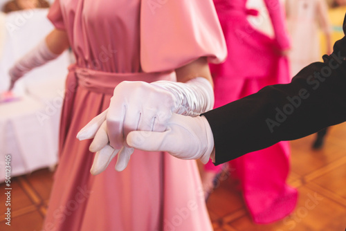 Couples dance on the historical costumed ball in historical dresses  classical ballroom dancers dancing  waltz  quadrille and polonaise in palace interiors on a wooden floor  opera gloves close-up