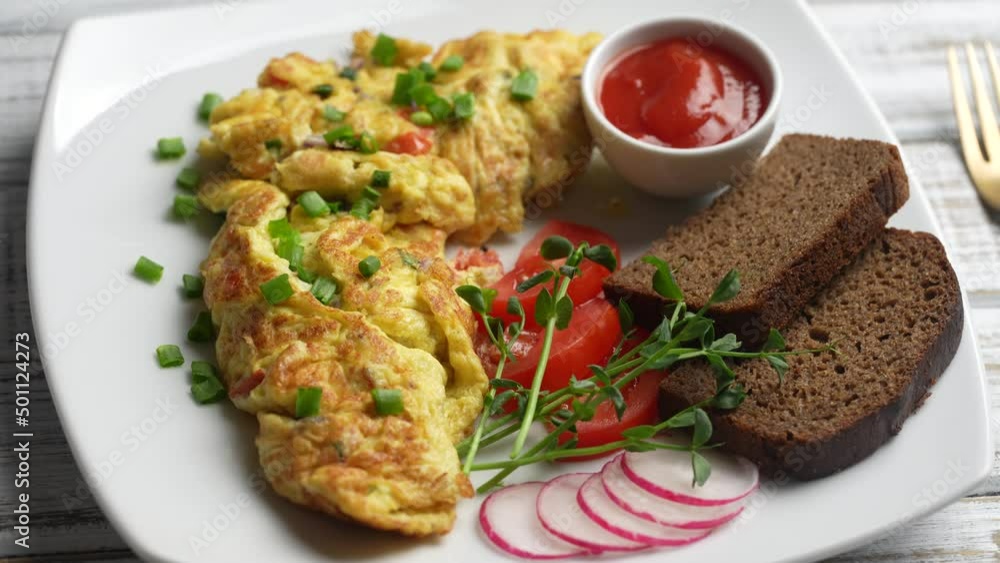 Stuffed omelette with onions, tomato, pepper, eggs and cheese in plate on white wooden background with fork. Healthy diet food for breakfast. Tasty morning food. Top view, close up, rotates Stuffed omelette with onions, tomato, pepper, eggs and cheese in plate on white wooden background with fork. Healthy diet food for breakfast. Tasty morning food. Top view, close up, rotates