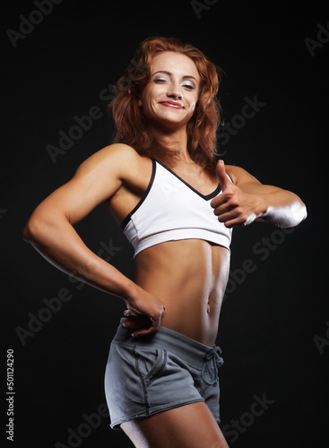 Young redhead woman in sportswear posing on a black background © Raisa Kanareva