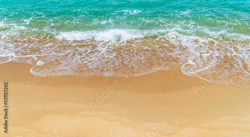 Sand beach seaside with white foamy and wave from blue sea, landscape seashore in summer season