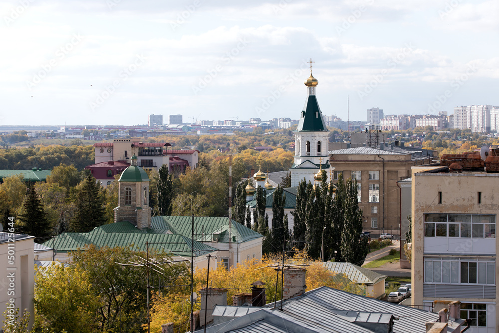Fototapeta premium View of roofs of buildings and dome of church with cross in city center