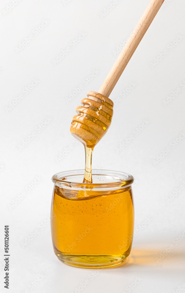 Honey pot and dripping honey with wooden spoon Honey pot and dripping honey with wooden spoon