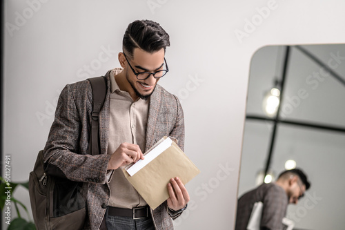 A young man in stylish jacket reading papers photo