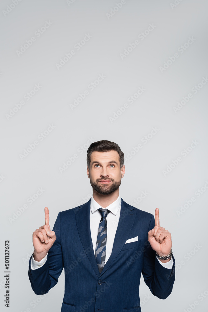 positive economist looking up and pointing with fingers isolated on grey. positive economist looking up and pointing with fingers isolated on grey.