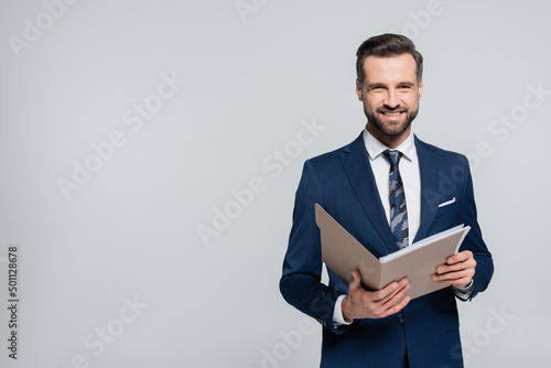 Obraz na płótnie happy economist with folder smiling at camera isolated on grey.
