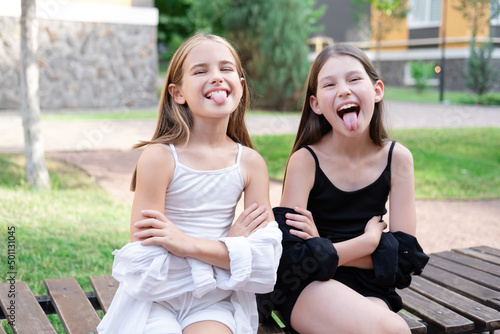happy and lucky to have a sister. two girls outdoors in black and white clothes. good and bad. obedient and harmful. fraternal twins teen sisters.
