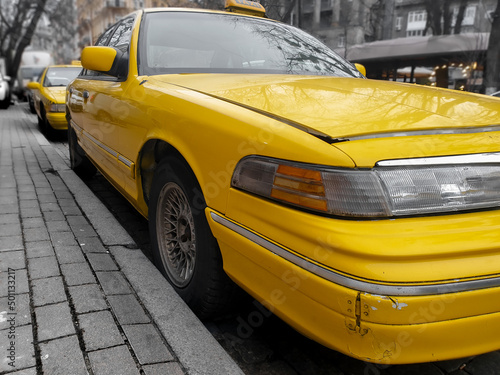 Closeup of old rusty yellow taxi with broken bumper and peeling off paint