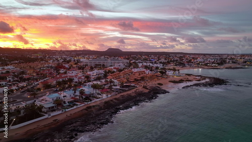 Night view of Corralejo city. Top view sunset cityscape. Bird eye view of the Canary islands, Spain. Night city near the calm sea bay. Sunset sky over the night city blocks.