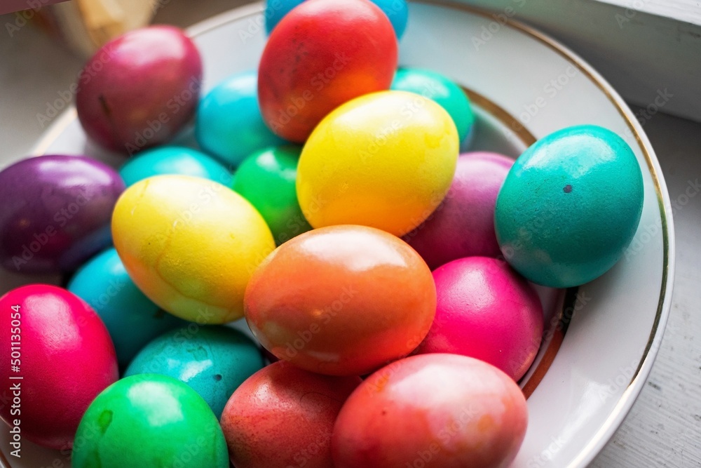 painted multi-colored chicken eggs in a wide white plate as a symbol of the holiday of Catholic believers painted multi-colored chicken eggs in a wide white plate as a symbol of the holiday of Catholic believers