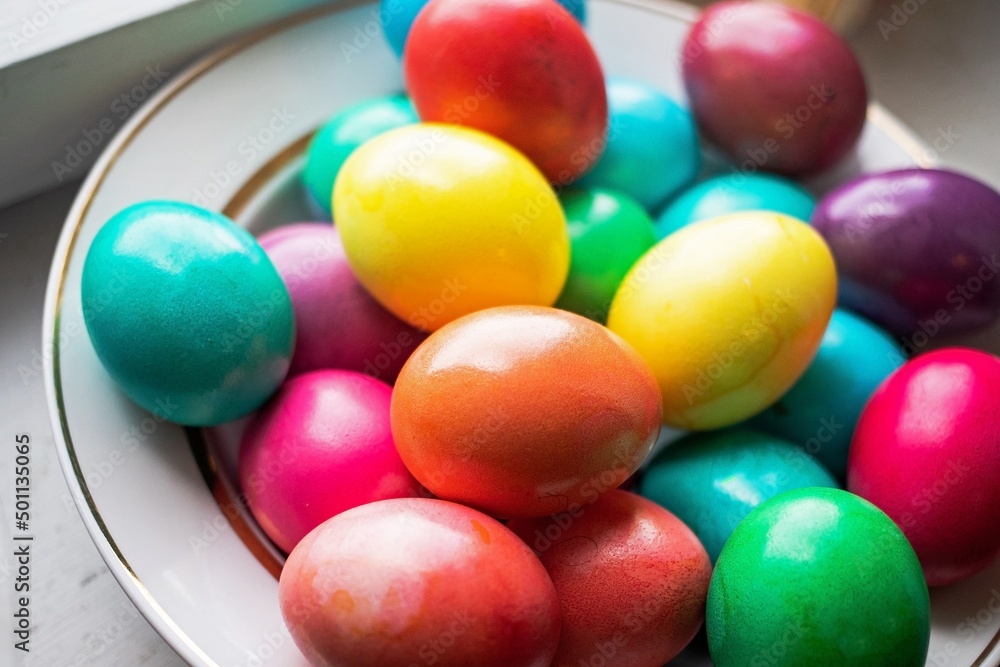 painted multi-colored chicken eggs in a wide white plate as a symbol of the holiday of Catholic believers painted multi-colored chicken eggs in a wide white plate as a symbol of the holiday of Catholic believers