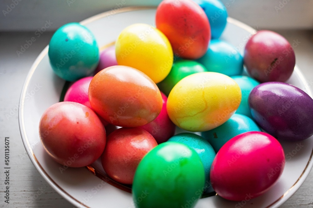 painted multi-colored chicken eggs in a wide white plate as a symbol of the holiday of Catholic believers painted multi-colored chicken eggs in a wide white plate as a symbol of the holiday of Catholic believers