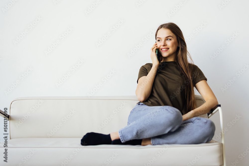 Young woman talk phone listen use laptop stay home sit sofa indoors