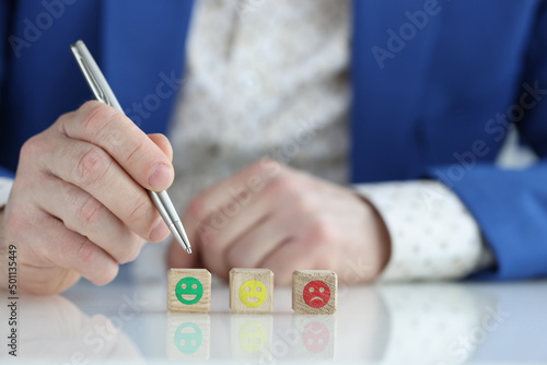 Man in business suit choosing assessment on scale of emoticons closeup