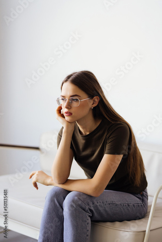 Young woman looking away sitting on couch at home.