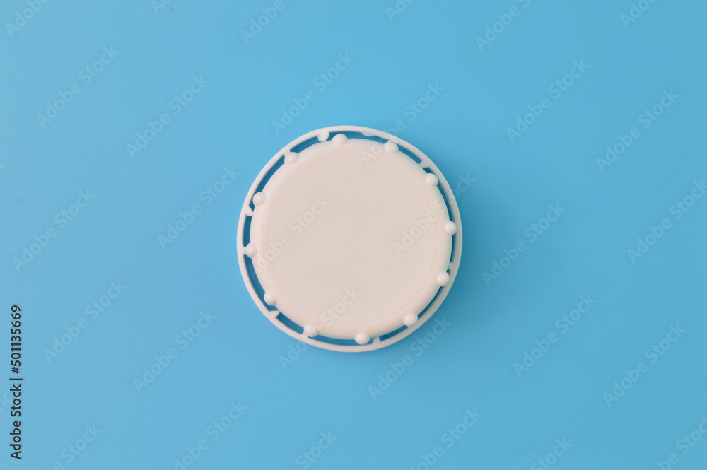 Close up view of white bottle cap isolated on a blue background Close up view of white bottle cap isolated on a blue background