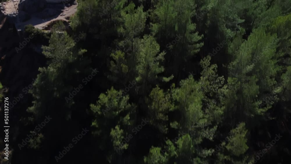 Ocean harbor landscape filmed from the mountain peak with green tropical forest. Aerial drone footage of greenery trees and blue sea with swimming nautical vessels on water surface at warm summer day. Ocean harbor landscape filmed from the mountain peak with green tropical forest. Aerial drone footage of greenery trees and blue sea with swimming nautical vessels on water surface at warm summer day.