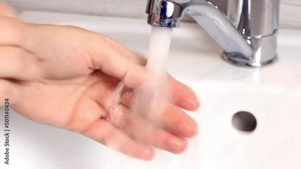 Caucasian woman washes hands with water in the bathroom to prevent infection Caucasian woman washes hands with water in the bathroom to prevent infection