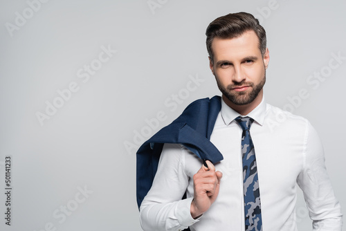 businessman in white shirt holding blazer and looking at camera isolated on grey.