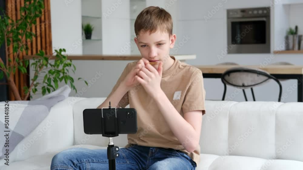 Teenage boy learns to play the folk musical instrument jew's harp online. Distance music education or hobby. Slow motion Teenage boy learns to play the folk musical instrument jew's harp online. Distance music education or hobby. Slow motion