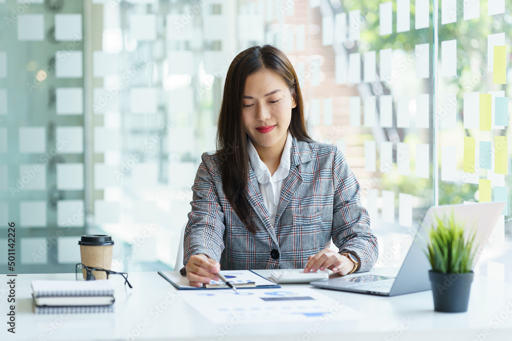 Portrait of young Asian businesswoman holding pen and using laptop in modern office, to analysis accounting chart data. Portrait of young Asian businesswoman holding pen and using laptop in modern office, to analysis accounting chart data.