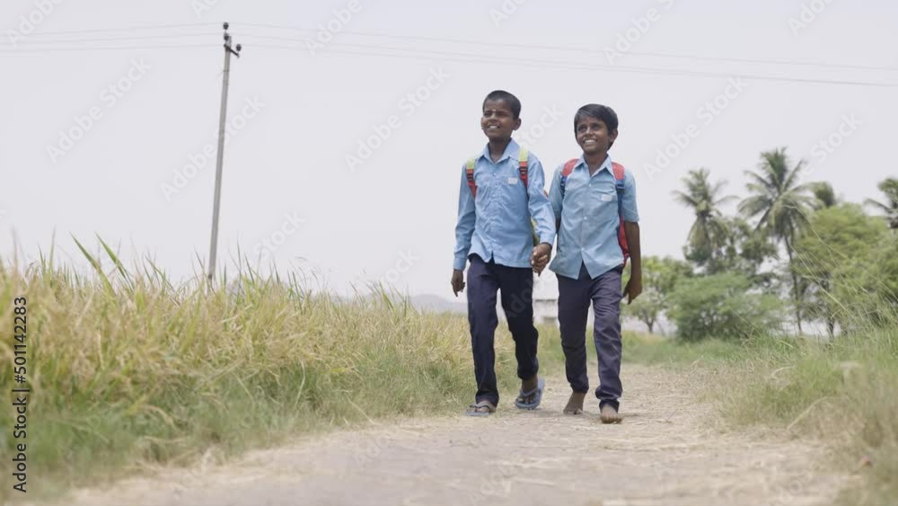 Village teenager kids in uniform by holding hands going to school on rural roads - concept of education, friendship and comminution Village teenager kids in uniform by holding hands going to school on rural roads - concept of education, friendship and comminution
