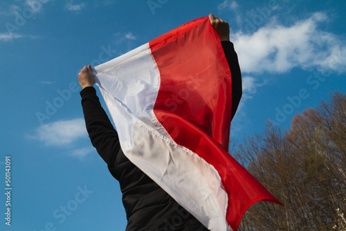 Woman holding flag of Poland against blue sky. 3 May Polish Constitution Day (3rd May National Holiday) or Independence Day celebration. photo